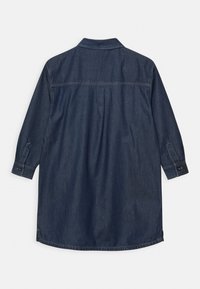 Šaty z tmavého denimu s dlouhými rukávy, knoflíkovými manžetami, zadním yoke a prošíváním na bílém pozadí.