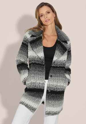 Gebreide jas in gradaties van zwart, grijs en wit. Heeft een brede kraag, een rij knopen aan de voorkant en twee zijzakken. Zacht, gestructureerd materiaal.