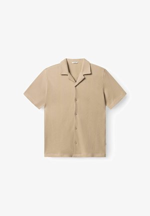 Camicia beige a maniche corte con bottoni e colletto alla coreana, con righe verticali strutturate, distesa su uno sfondo bianco.