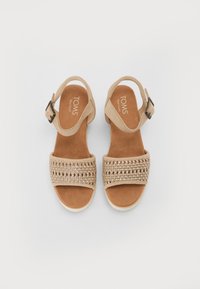 Sandales en daim beige avec une texture tissée sur la partie supérieure, sangle à boucle réglable et doublure intérieure douce. Design à semelle plate.