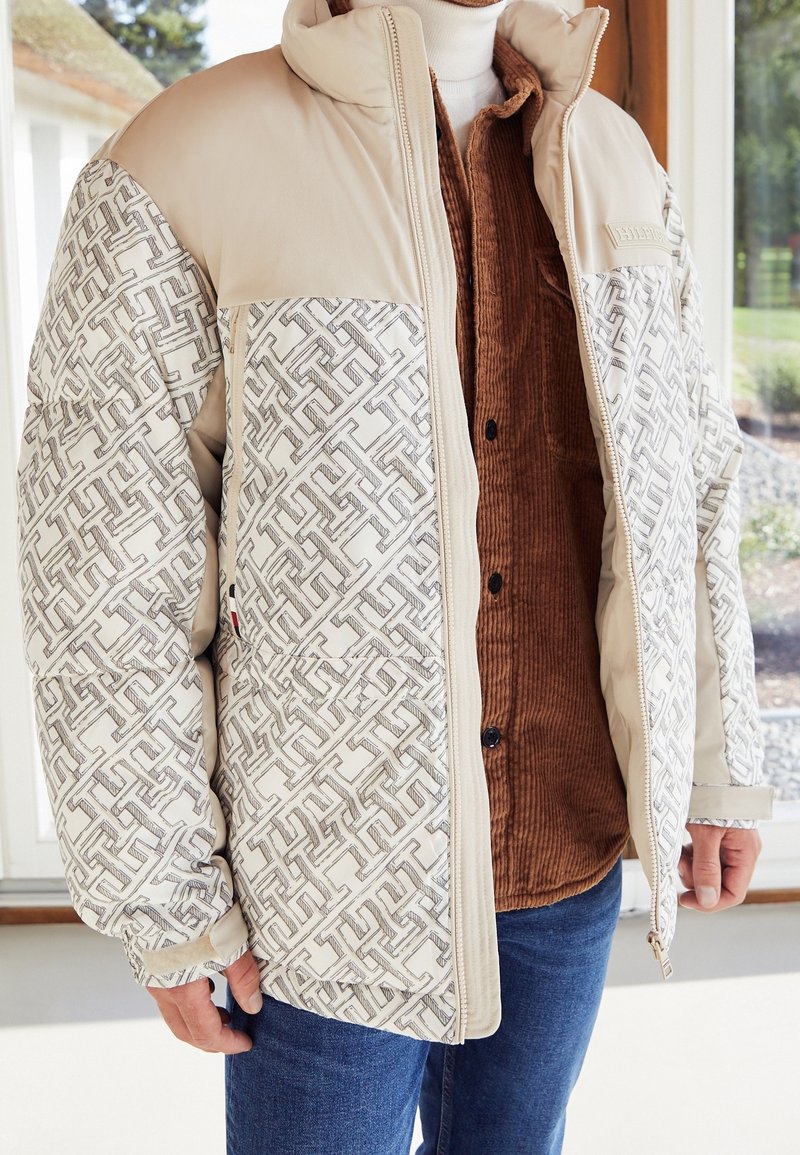 Beżowa pikowana kurtka z tkaniną o teksturowanym wzorze z jednej strony i gładkim materiałem z drugiej. Zamek błyskawiczny z przodu i wysoki kołnierz.