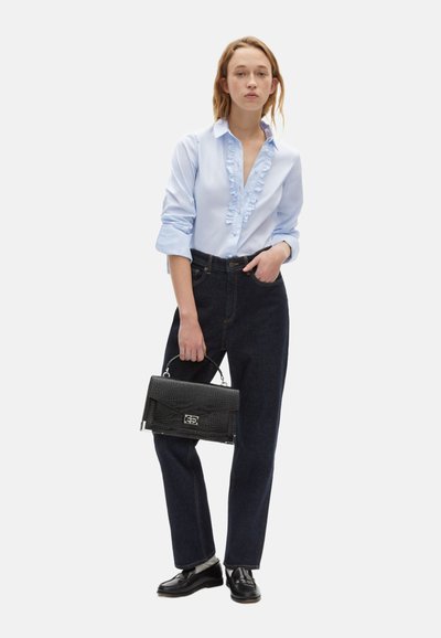Camisa de botones azul claro con fruncido en el frente, vaqueros de tiro alto azul oscuro y un bolso negro texturizado, combinados con mocasines negros.