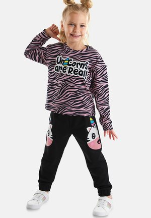 Zwarte joggers met een eenhoorngezicht-print, roze en witte accenten; roze shirt met zebra-strepen en lange mouwen met de tekst "Eenhoorns zijn echt!"