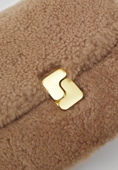 Brun fleecekuvert med en slät, metallklämma i guldton som har två sammanlänkade former, vilket framhäver en mjuk textur och varm färg.