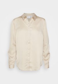 Chemise en satin beige à manches longues, col classique, fermeture boutonnée sur le devant, et ourlet légèrement arrondi. Texture lisse, design minimaliste.