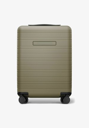 Valise rigide compacte vert olive avec des rainures horizontales et quatre roues multidirectionnelles noires, vue de face sur fond blanc.