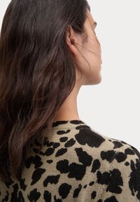 Maglione a maglia in verde oliva con stampa leopardata nera. Presenta un collo rotondo e un tessuto testurizzato, evidenziando un design aderente.