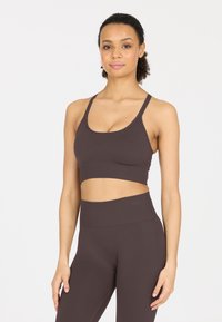 Brauner Sport-BH mit breitem Bund und dicken Trägern, kombiniert mit passenden hochgeschnittenen Leggings aus einem glatten, dehnbaren Material.