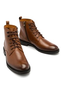 Brązowe skórzane botki za kostkę z sznurowaniem i zamkiem błyskawicznym po boku, charakteryzujące się gładką fakturą i zaokrąglonym noskiem, osadzone na czarnej gumowej sole.