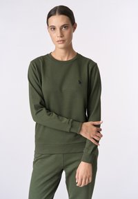 Felpa verde oliva con maniche lunghe, polsini e orlo a coste. Presenta un piccolo logo nero sul petto. Tessuto in morbido cotone misto.
