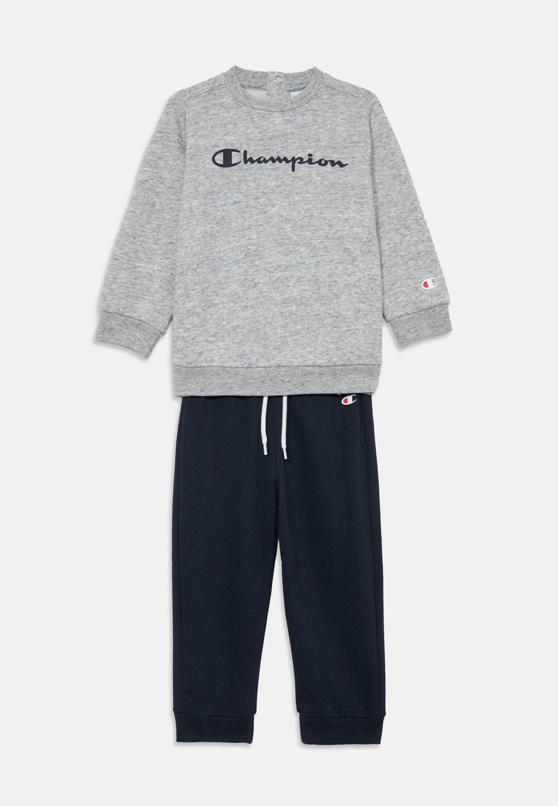 Γκρι φούτερ με λογότυπο "Champion" σε ναυτικό μπλε, στρογγυλή λαιμόκοψη, ριμπ μανσέτες. Ναυτικά παντελόνια με κορδόνι και ελαστικές μανσέτες, λογότυπο ραμμένο στο πόδι.