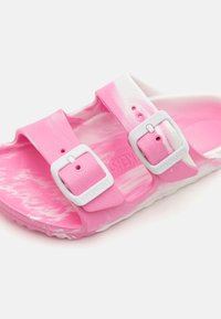 Sandalia Birkenstock con un diseño en mármol rosa, dos correas ajustables con hebillas blancas y una plantilla texturizada.