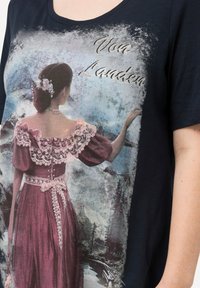 Camiseta de color navy con un estampado vintage que presenta a una mujer en un vestido rosa, con detalles de encaje y acentos florales contra un fondo de paisaje.