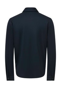 Chemise noire à manches longues avec col, vue de dos avec poignets boutonnés et tissu simple et lisse.