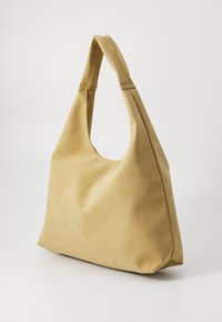 Sac à épaule en cuir tan avec une poignée courbée et une surface douce et texturée, comportant un compartiment principal spacieux et des détails de couture minimaux.
