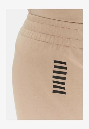 Pantaloni jogger beige con una fascia elastica in vita. Strisce nere creano un motivo di lato. Texture liscia con una silhouette aderente.
