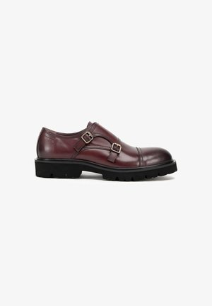Burgundy leather shoe with two metallic buckles, rounded toe, stitched detailing, and textured black rubber sole.