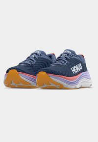 Blå löparskor med ett texturerat mesh-överstycke, vit och orange mellansula samt lila yttersula; har tydlig märkning på sidan.