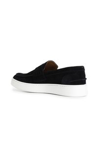 Černé semišové slip-on boty s bílou gumovou podrážkou. Mají plochý design a jemné švy na svršku. Hladká textura.