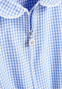 Blå og hvid ternet skjorte med rundet krave og lynlås med en blomst-formet trækkefane. Blød tekstur og let materiale.