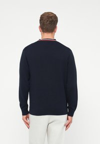 Ναυτικά πουλόβερ με μακριά μανίκια, ρίγες στις μανσέτες και στρογγυλή λαιμόκοψη, με κόκκινη και λευκή ριγέ κολάρο. Μαλακή υφή, ελαφρύ υλικό.