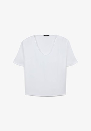 Blusa bianca a maniche corte con ampio scollo a V. Il tessuto appare liscio e leggero, con un taglio rilassato e svasato.