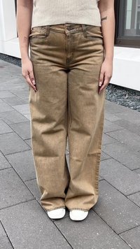 Svetlo rjavi široki jeans iz denima, z visokim pasom, vidnim šivom in stranskimi žepi, v kombinaciji z belimi športnimi copati.