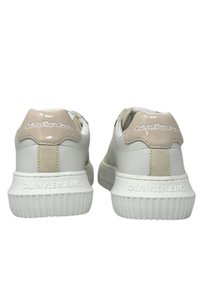 Sneakers bianchi in pelle con un accento crema sul tallone, suola in gomma testurizzata e marchio "Calvin Klein Jeans" in rilievo sul retro.