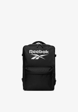 Czarny, prostokątny plecak z przednią kieszenią na suwak i białym logo Reebok umieszczonym nad kieszenią oraz górnym uchwytem z podwójnym suwakiem.