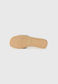 Tan rubber sole with wave pattern and grip texture. Features a light blue upper material with an embossed logo and smooth finish.
