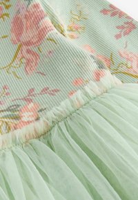 Květnaté mentolové šaty s ribnovaným korzetem pokrytým růžovými a žlutými květinami, doplněné o vrstvenou, průhlednou zelenou tylovou sukni.