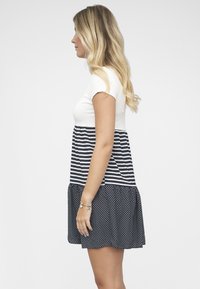 Robe rayée avec le haut blanc et le bas bleu marine orné de pois. Manches courtes et jupe évasée créent une silhouette décontractée.