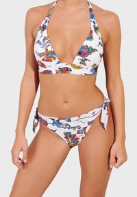Bikini set featuring a halter neck top and tie-side bottoms. Made of white fabric with vibrant multicolored abstract patterns throughout.