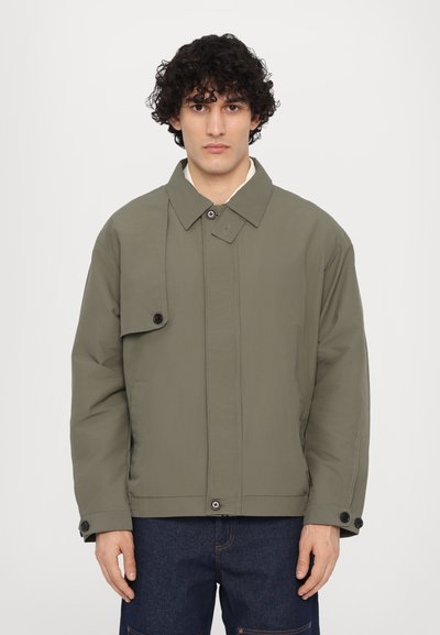 Veste vert olive avec un col, fermeture à boutons et une poche à rabat. Présente une coupe décontractée et un tissu texturé, adaptée au style décontracté.