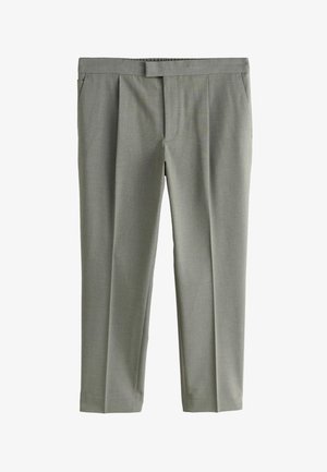 Uomo che indossa pantaloni grigio chiaro su misura con piega frontale, tasche laterali, mano casuale nella tasca sinistra e camicia bianca infilata.
