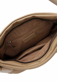 Intérieur d'un sac en cuir tan avec un revêtement en tissu brun, comprenant une poche zippée et deux poches ouvertes, le tout avec des textures lisses.