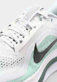 Baskets Nike avec un dessus en maille blanche, des accents vert menthe, un logo swoosh noir et une semelle texturée. Caractéristiques d'un design à lacets et d'un col rembourré.