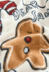 Couverture en polaire avec un design de bonhomme en pain d'épice en marron et blanc, avec des accents rouges et blancs, et le texte "CHER SAN" en noir.