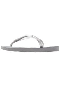 Harmaa flip-flop, joka on valmistettu kumista, ja jossa on teksturoitu pohja sekä ohuet, läpinäkyvät hihnat. Suunnittelu on yksinkertainen ja minimalistinen.