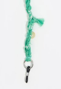 Cintura in tessuto verde intrecciato con bordi sfrangiati, dotata di una perlina tonda e un anello in metallo argento con un gancio nero all'estremità.