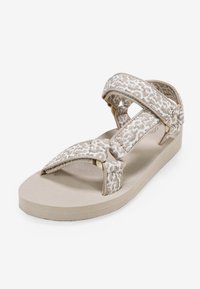 Sandal beige con cinturini in tessuto intrecciato con un motivo geometrico, suola piatta in gomma e chiusure regolabili per una vestibilità sicura.