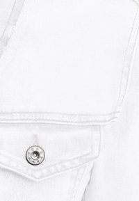 Chaqueta de mezclilla blanca con un acabado texturizado, costuras visibles y un botón metálico con diseño de estrella en el bolsillo del pecho.
