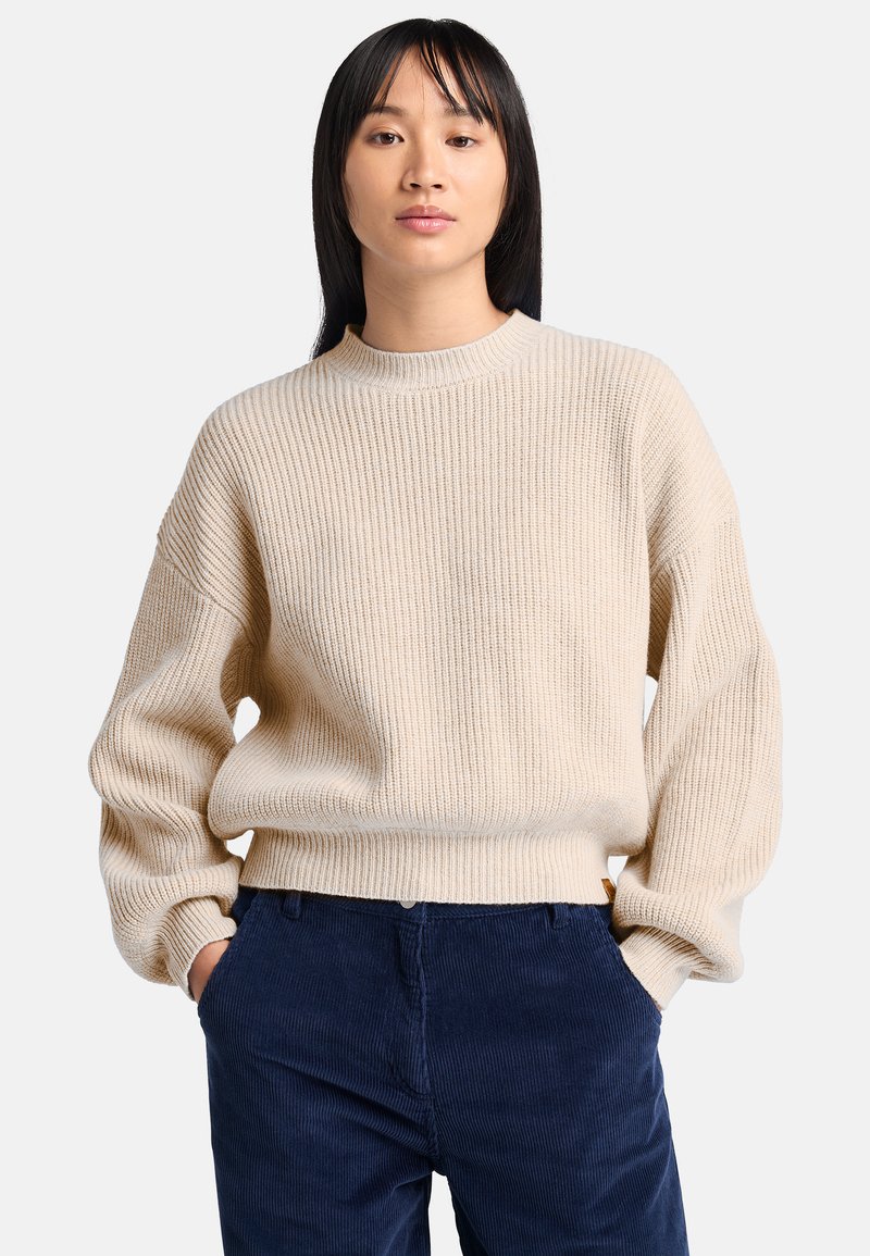 Beige ribbad stickad tröja med rundad halsringning och nedhasade axlar, stylad med marinblå manchesterbyxor, som har en avslappnad passform och mjuk textur.