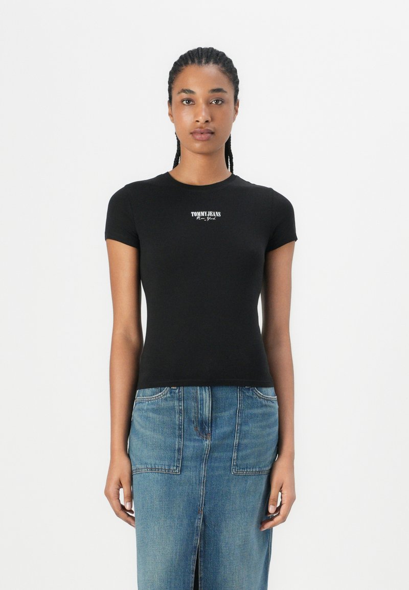 Melnā īsām piedurknēm T-kreklā ar pieguļošu dizainu un baltu "TOMMY JEANS" logo uz krūtīm, saskaņots ar zilu džinsa svārku.