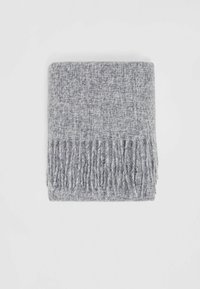 Couverture tissée grise avec des bords à franges, dotée d'un matériau texturé et doux, ainsi que d'un motif neutre et chiné.