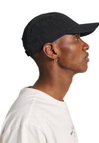 Czarna czapka z zakrzywionym daszkiem i panelami siateczkowymi, zapewniająca przewiewny design. Nosi ją osoba z krótkimi brązowymi włosami i białą koszulką.