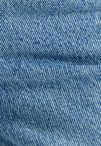 Tela de mezclilla azul claro, con una textura suave y un patrón de sarga visible. No hay acentos o herrajes notables visibles.