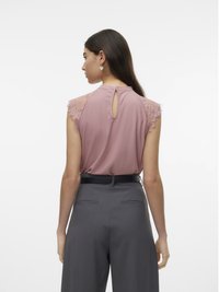 Vista posteriore di un top senza maniche rosa con dettagli in pizzo, abbinato a pantaloni grigi a gamba larga e una cintura nera. Apertura a forma di chiave sul collo.