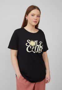 Zwarte katoenen t-shirt met een crèmekleurige grafische print met de tekst "SALE CLUB" en een zonontwerp; relaxte pasvorm met korte mouwen en ronde hals.
