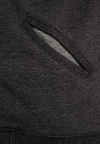 Sudadera negra de tela con un bolsillo lateral diagonal con un interior gris liso, texturizado, y con un cinturón acanalado.